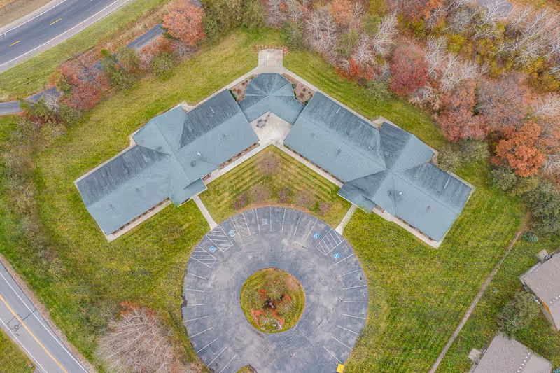 Aerial view of Nordic Woods Assisted Living building with circular driveway and trees.