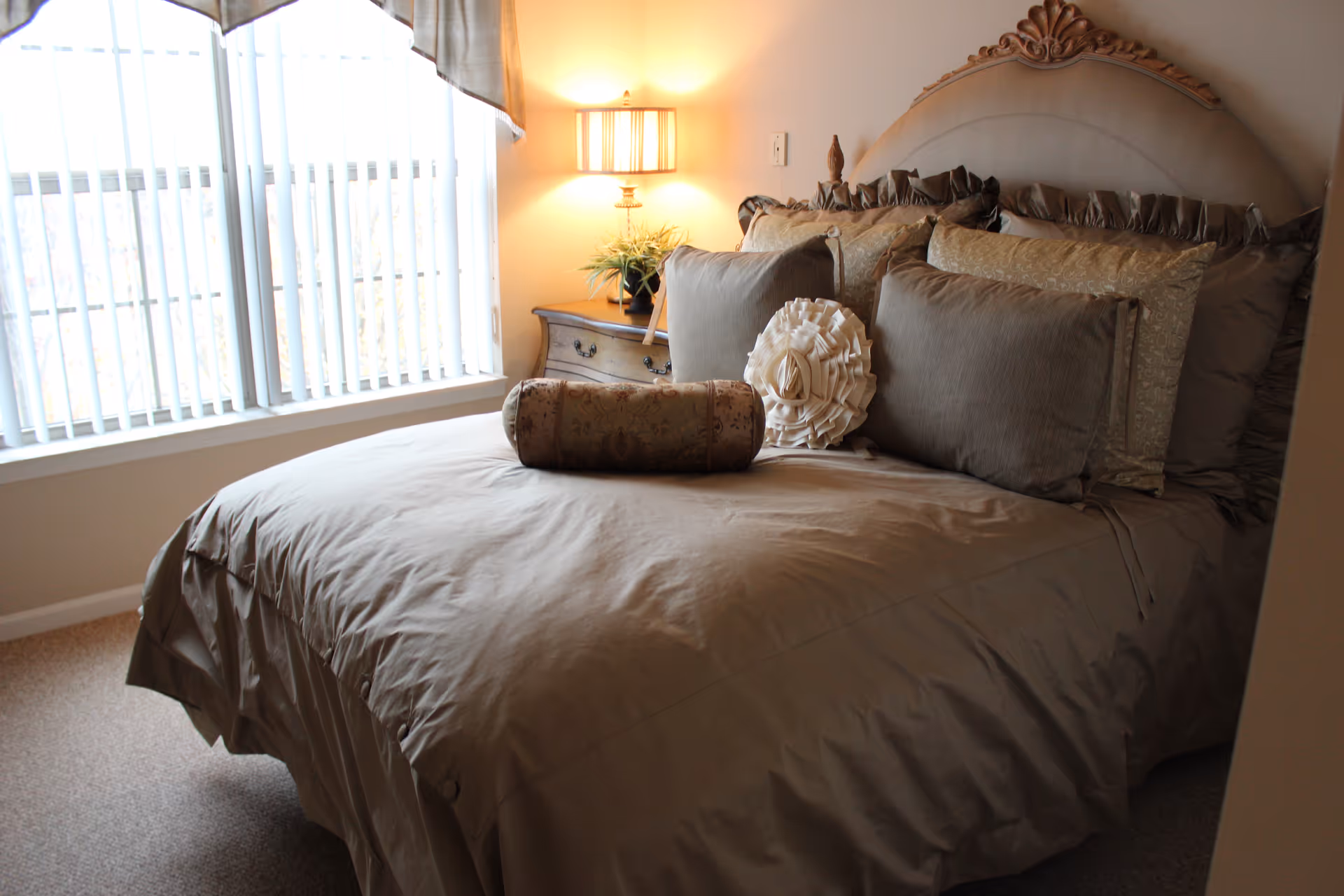 A neatly made bed with decorative pillows in a cozy bedroom near a window.