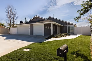 Exterior view of a single-story facility with a three-car garage and a green lawn.
