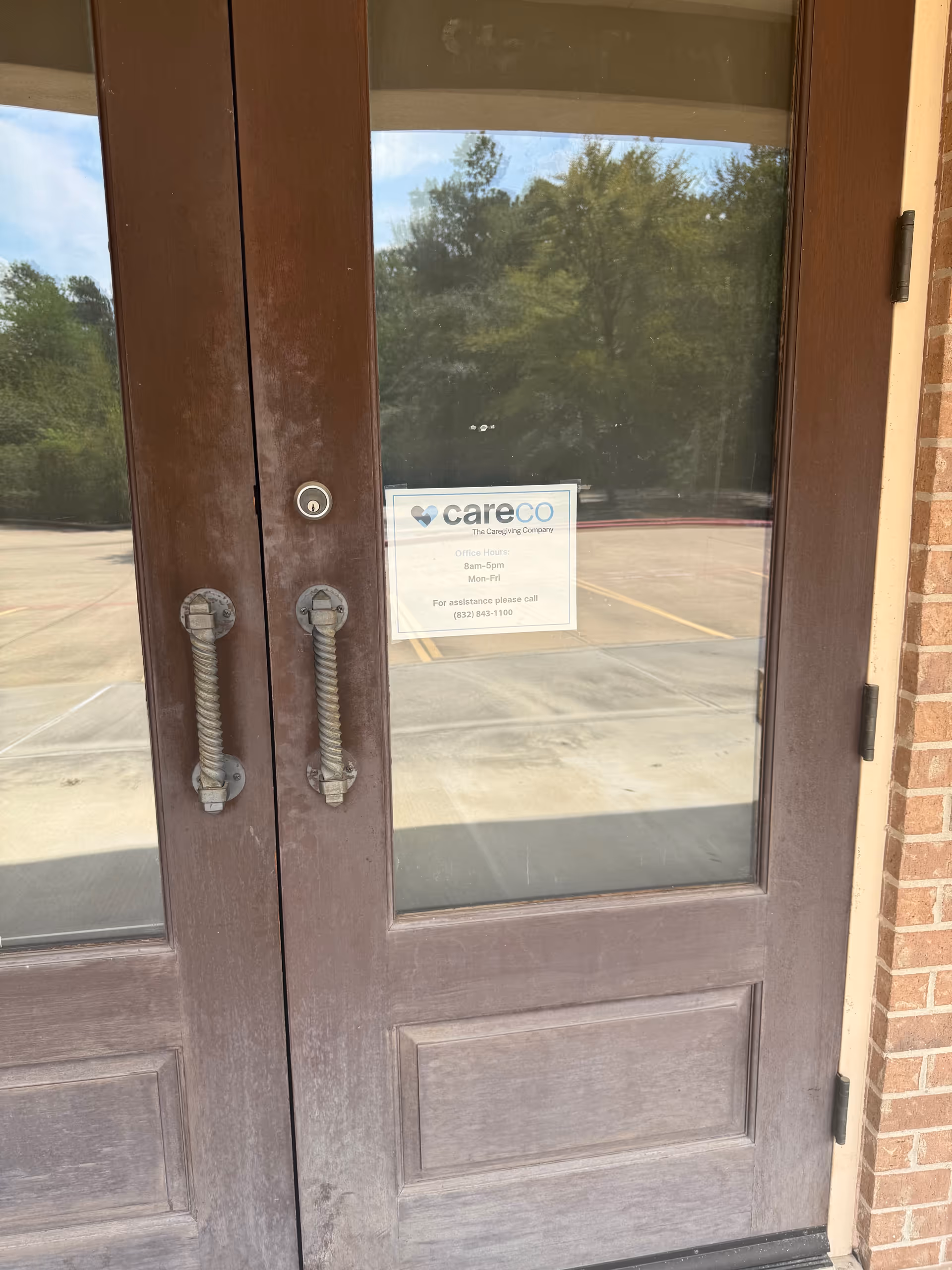 Double wooden doors with glass panels and a CareCo sign at the building entrance.