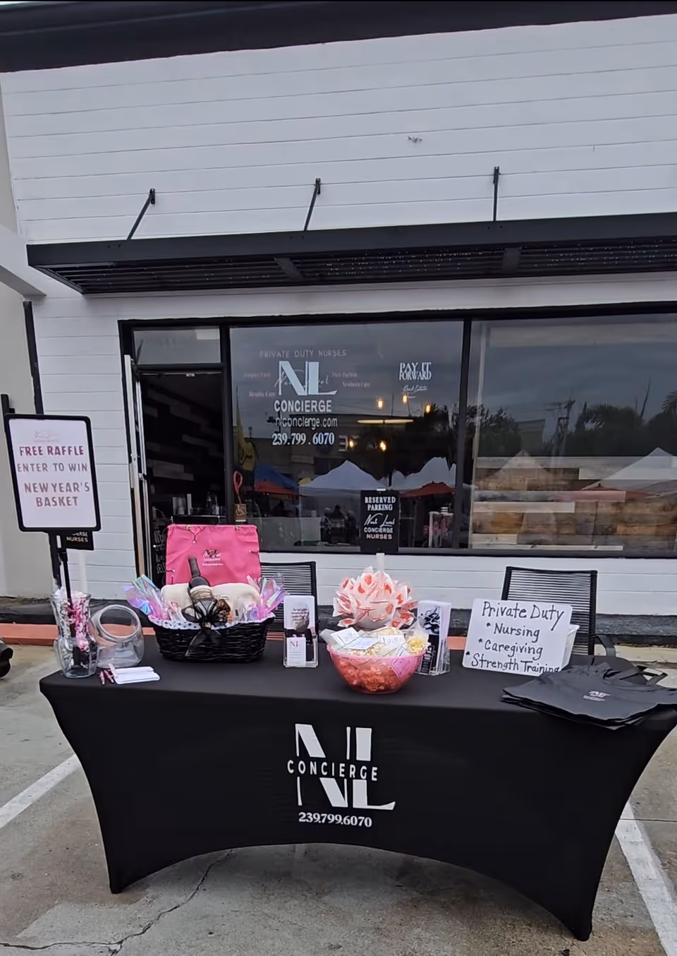 Exterior storefront of Next Level Concierge with a black tablecloth displaying prizes outdoors.