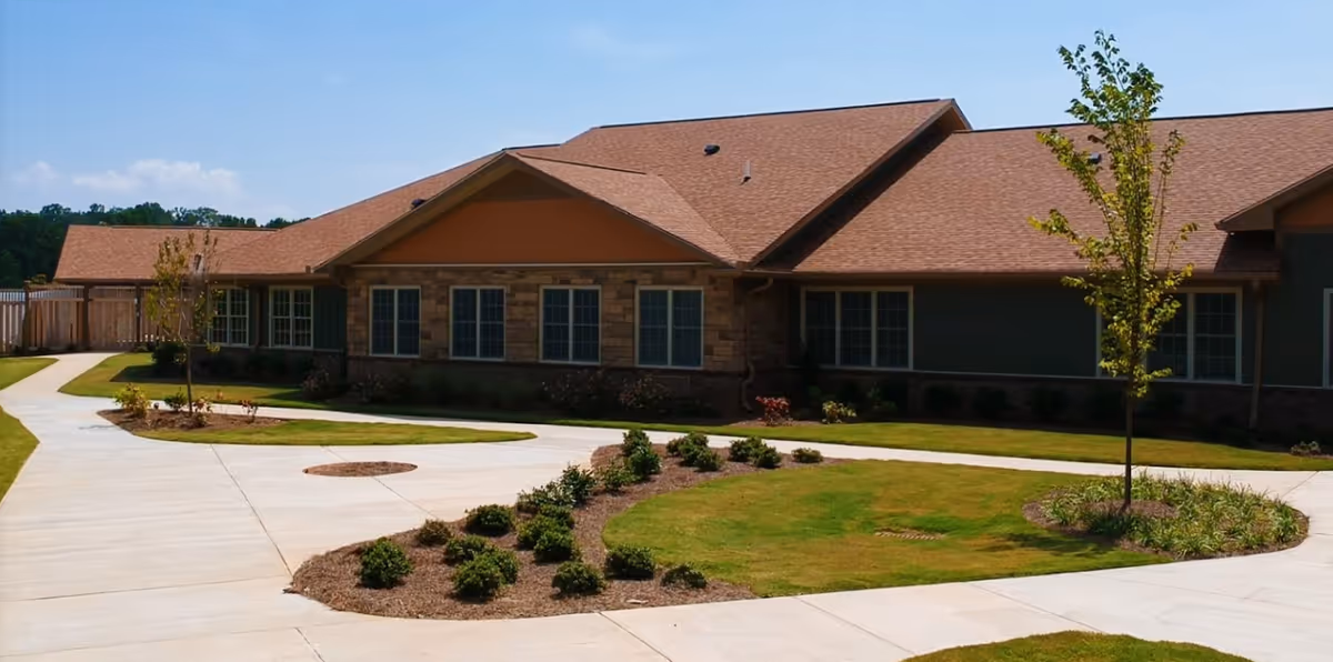 Single-story brick senior living facility exterior with manicured lawn and curved driveway.