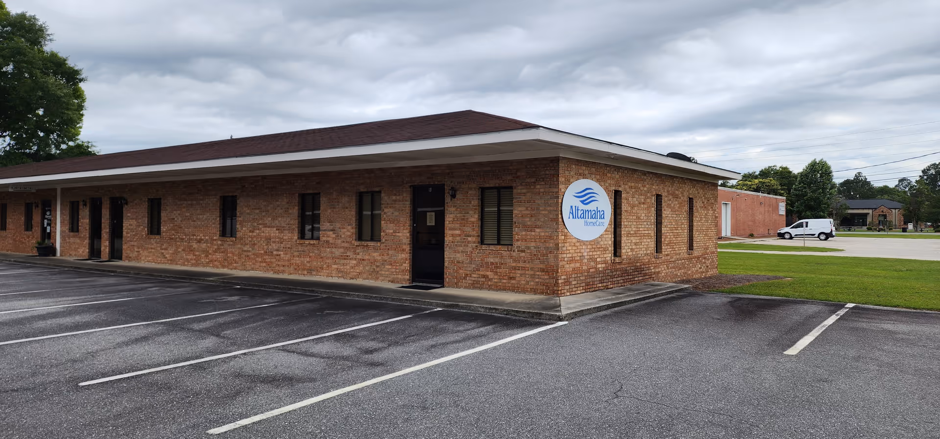 Exterior view of a brick Altamaha HomeCare building with a parking lot.