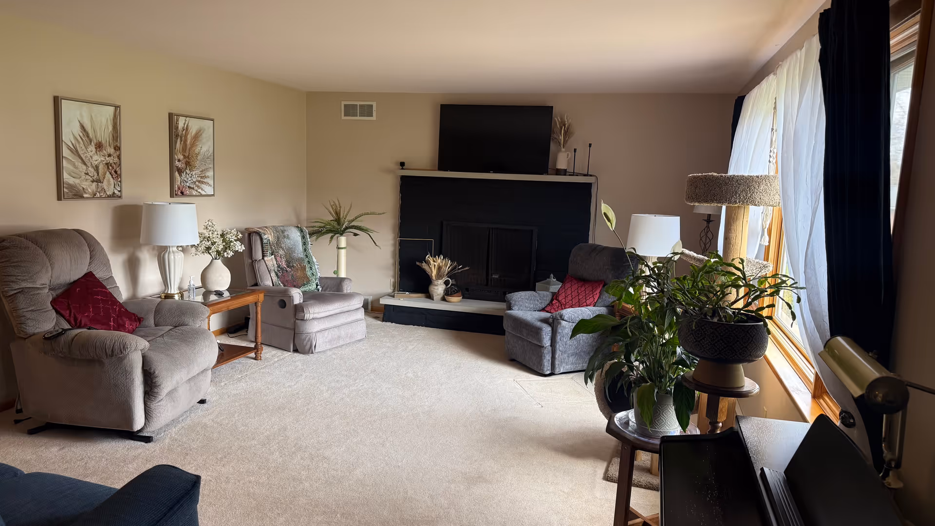 Cozy living room with multiple recliners and a fireplace beneath a mounted TV.