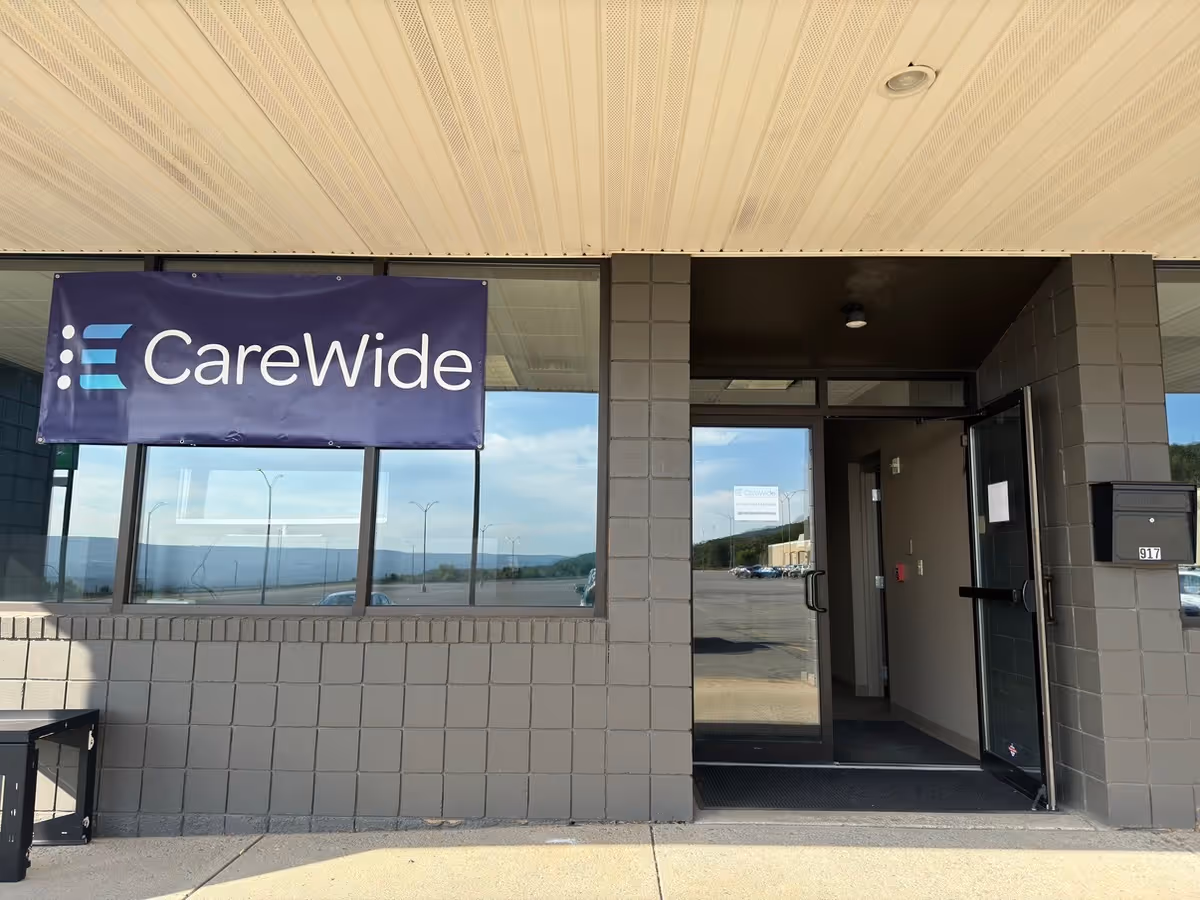 Entrance to CareWide facility with blue banner on gray brick exterior.