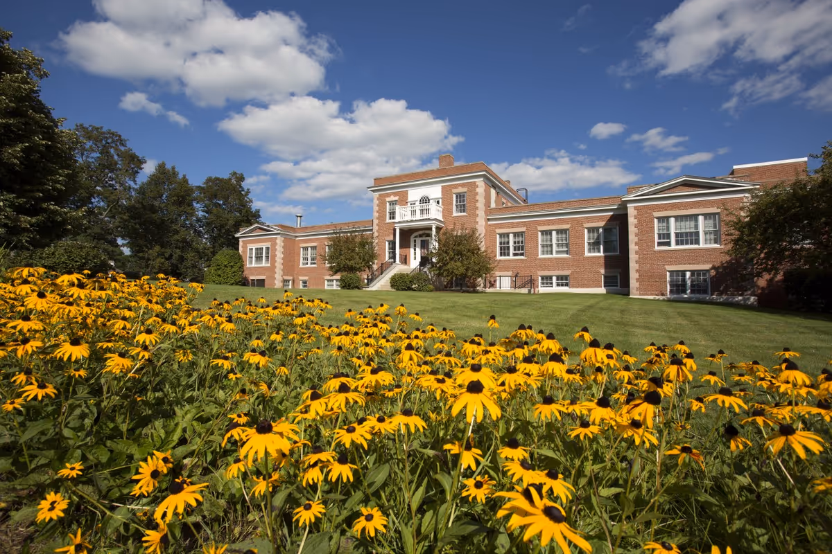 Exterior view of Nashoba Park facility with brick building, lawn, and yellow flowers in foreground.