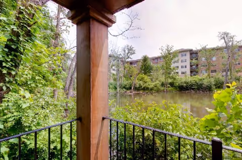 View from a balcony overlooking a pond and trees near the senior living campus.