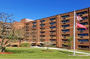 Brick Westbrook Towers exterior with flags, a manicured lawn, and a walkway in front.