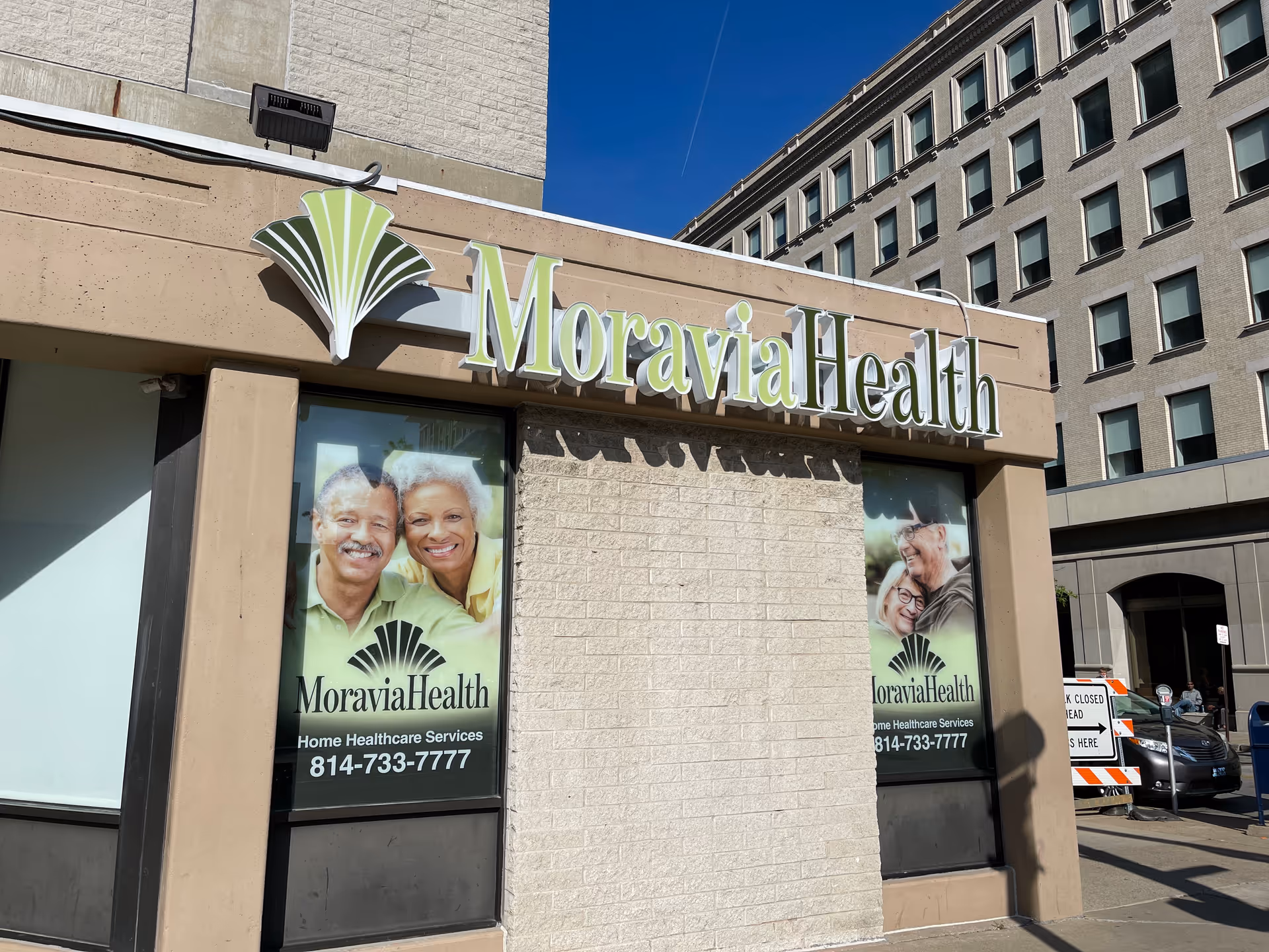 Moravia Health storefront sign on brick building with promotional banners