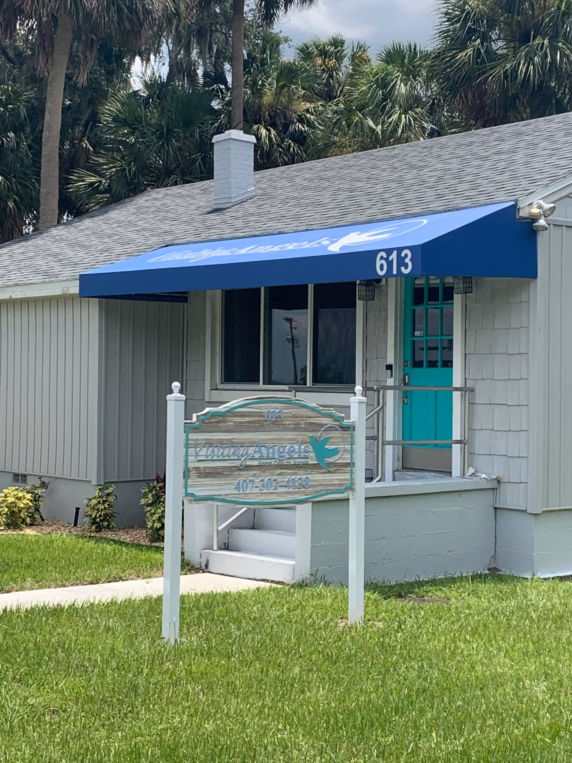 Exterior of a Visiting Angels facility with blue awning, front sign, and teal door.
