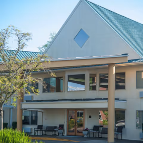 Timberhill Place exterior building with entrance and covered front porch seating.