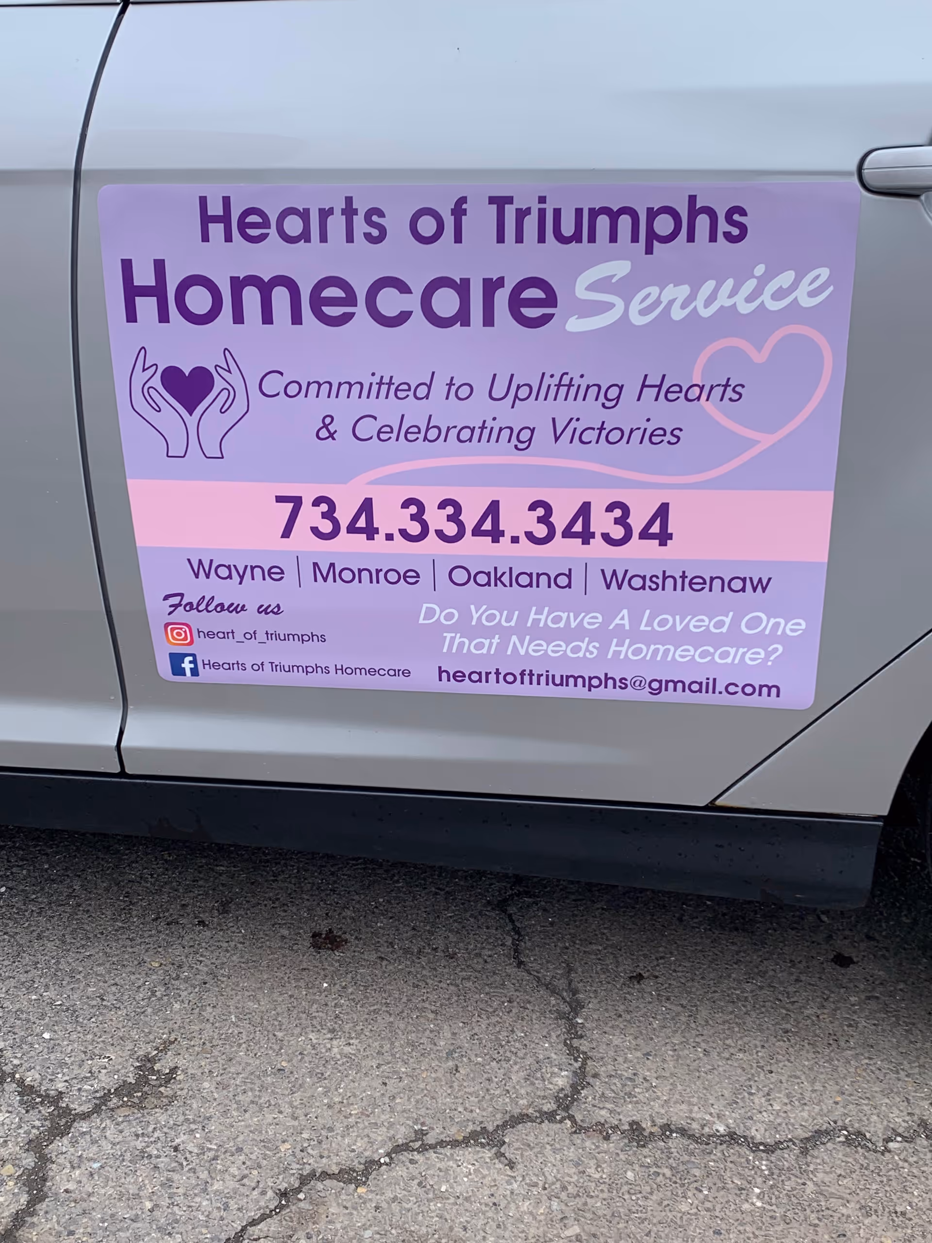 Purple sign on a silver van advertising Hearts of Triumphs Homecare Service.
