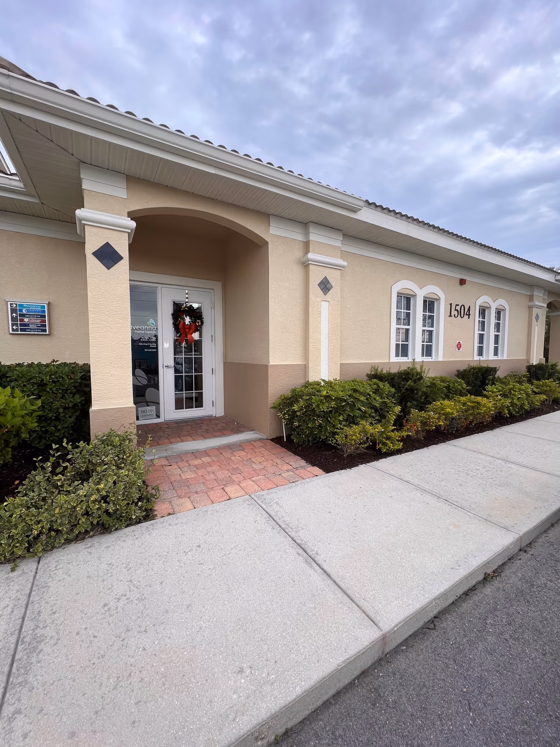 Exterior view of Aveanna Home Health entrance with wreath, arched doorway, and shrubs.