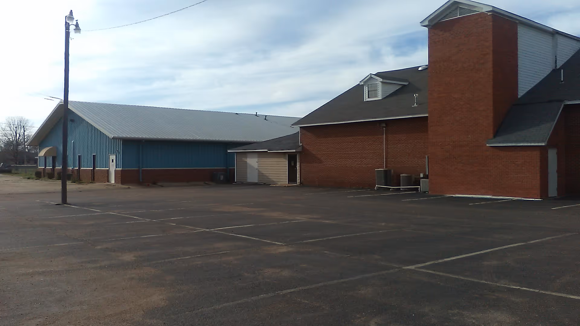 Exterior view of a Mid-Delta senior living facility with brick and blue siding, parking lot.