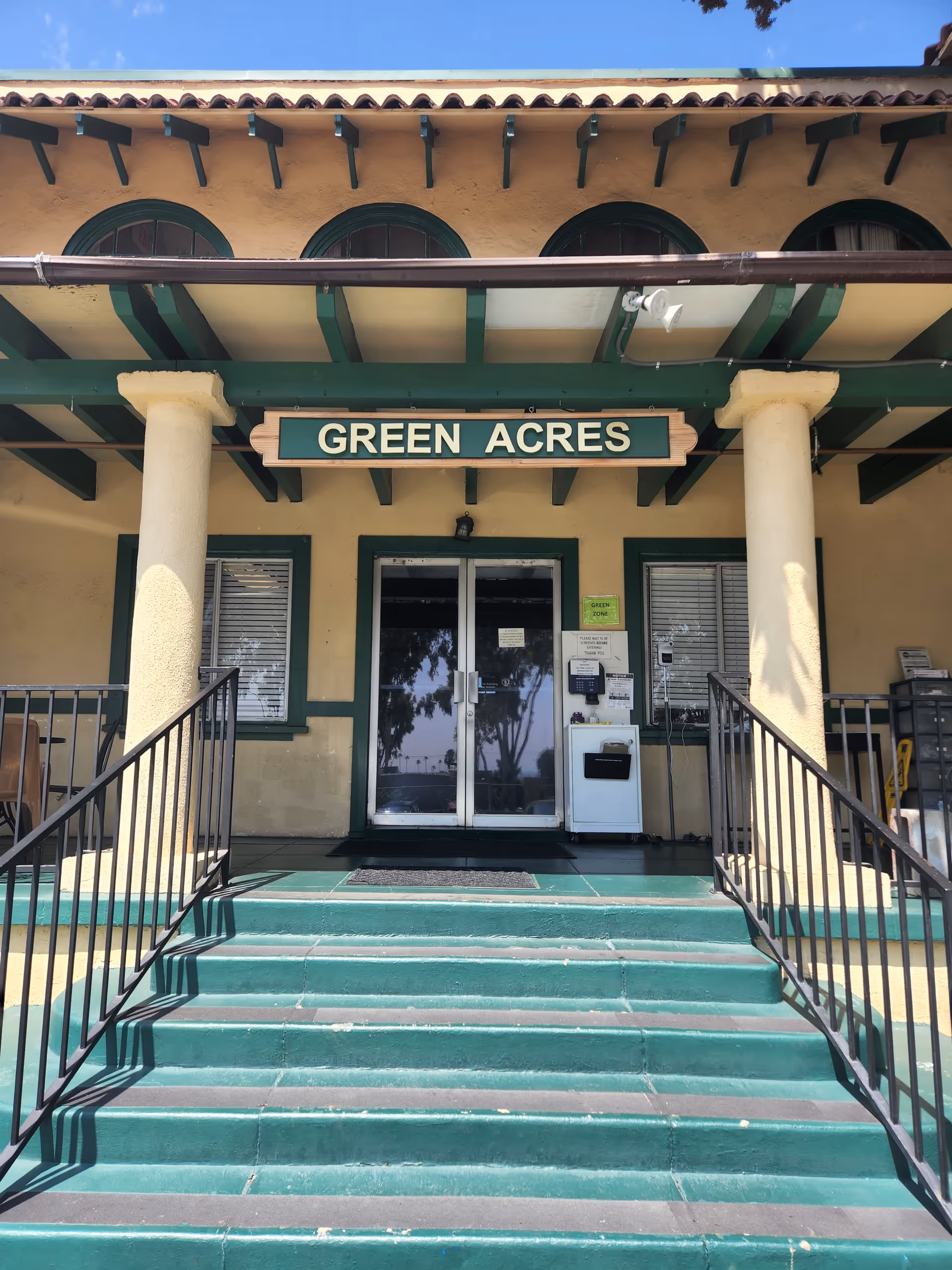 Front entrance of Green Acres Lodge with green steps and columns.