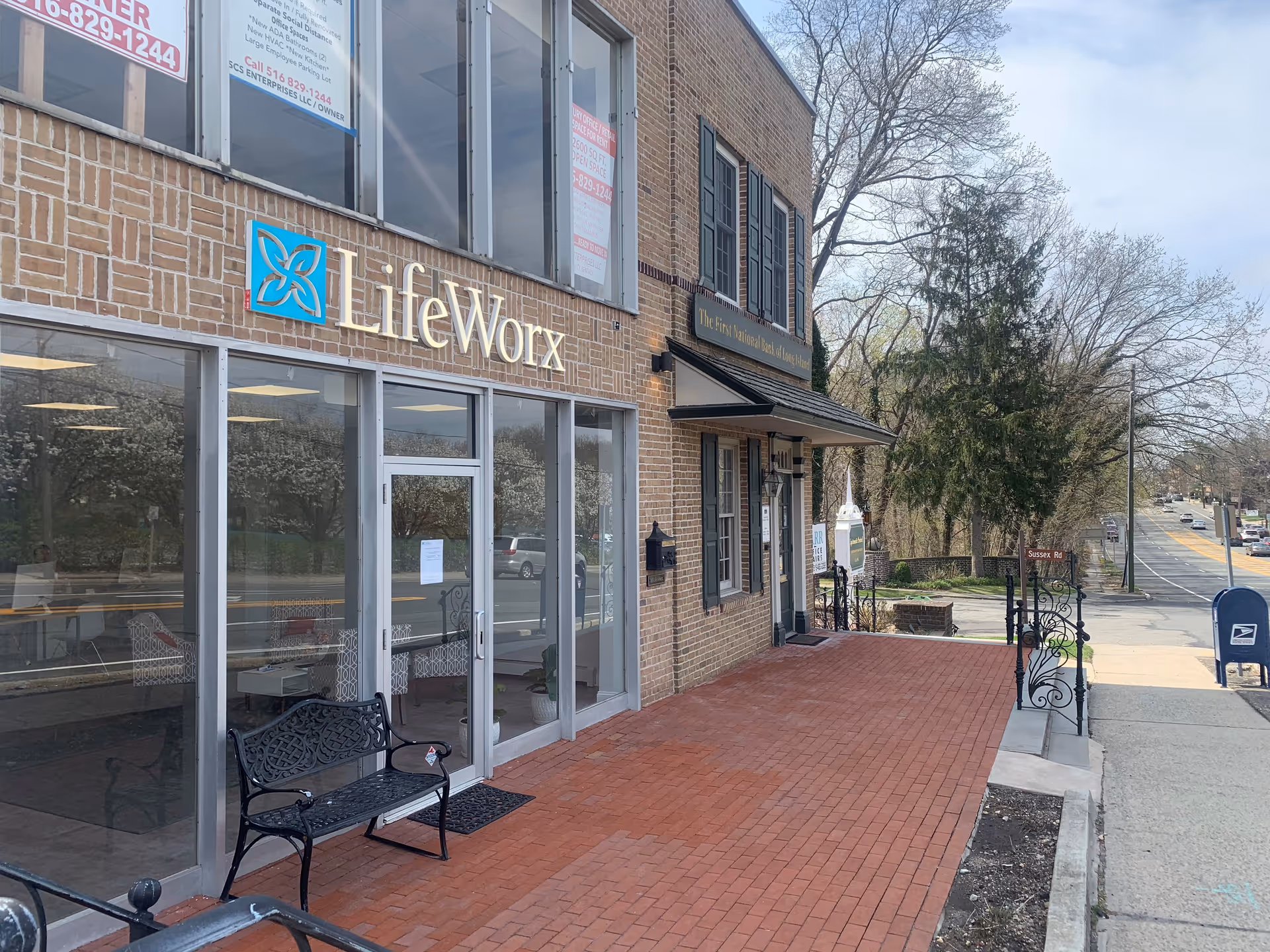Exterior view of LifeWorx Home Care storefront with brick building and bench.