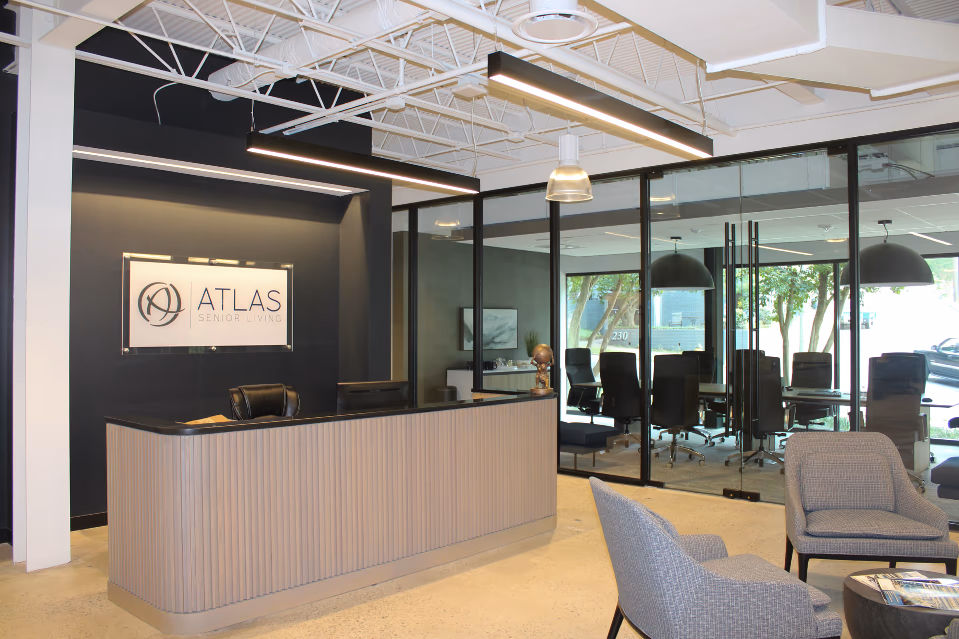 Reception desk in Atlas Senior Living lobby with glass-walled conference room.