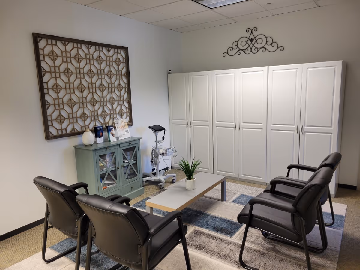 Lounge area with black chairs arranged around a low table and white cabinets.
