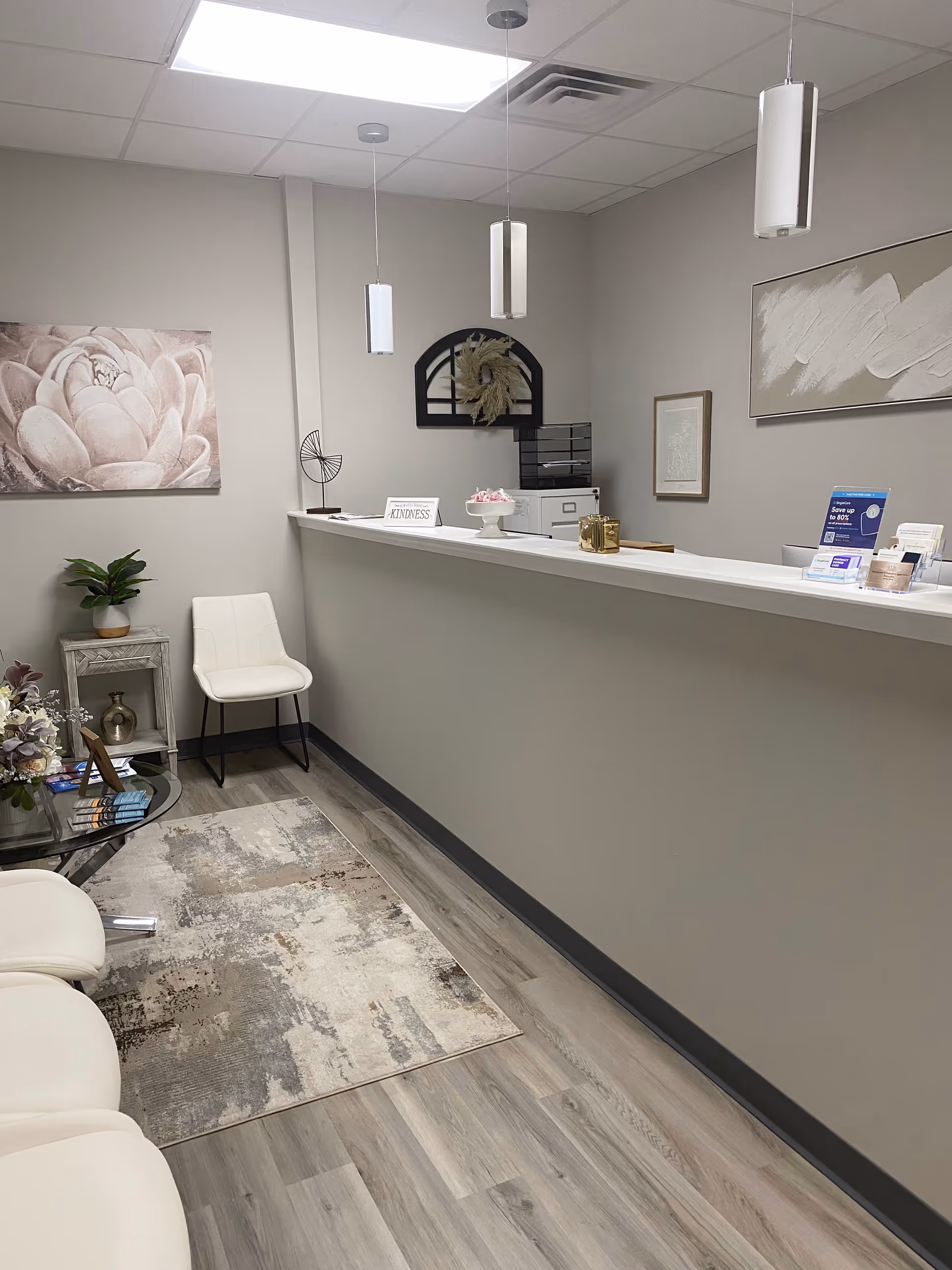 Reception desk area inside Rosewell Home Health Agency with white chairs and wall art.