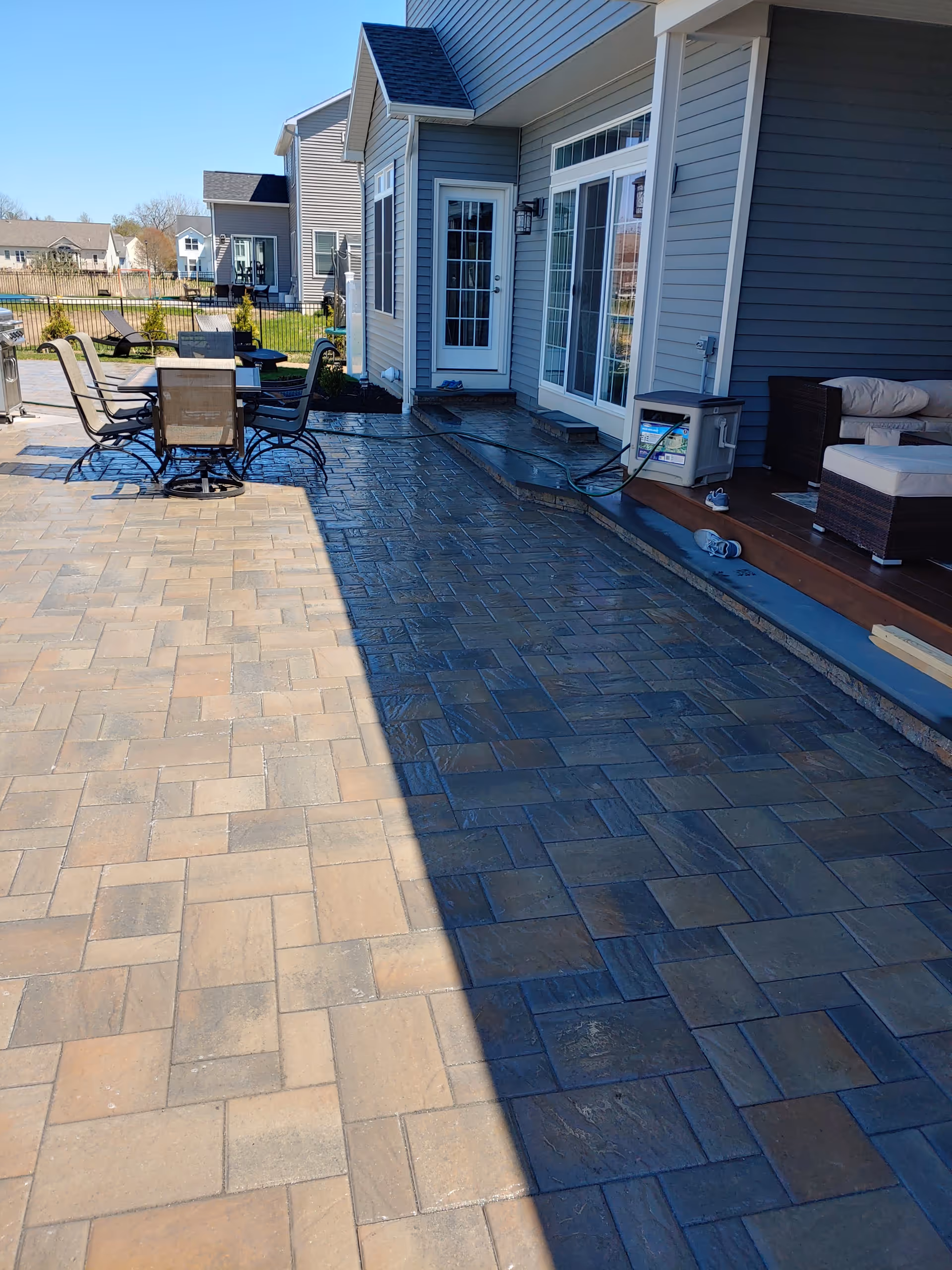 Blue-gray building exterior with a paved patio and outdoor seating.