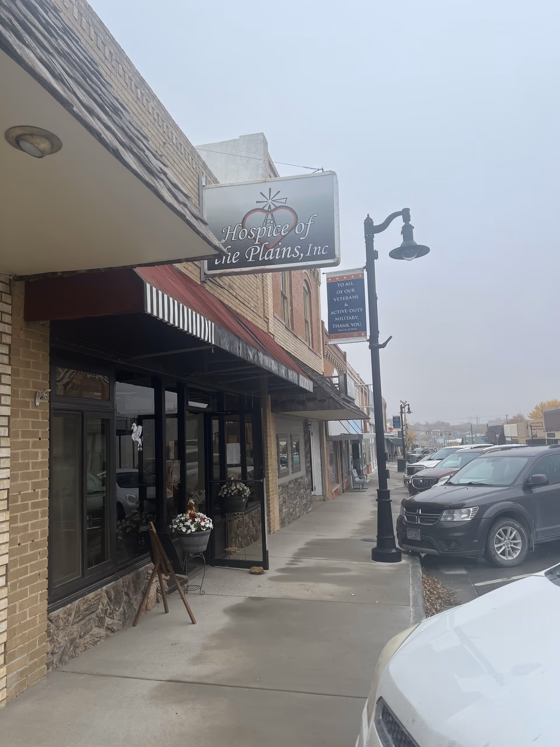 Exterior street view of Hospice of the Plains storefront with sign and sidewalk.