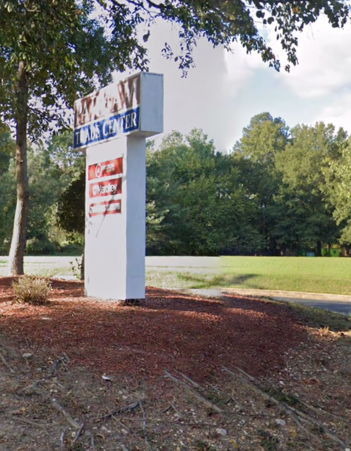 Tall white exterior sign for Angels on Earth Home Care beside a mulched landscape.