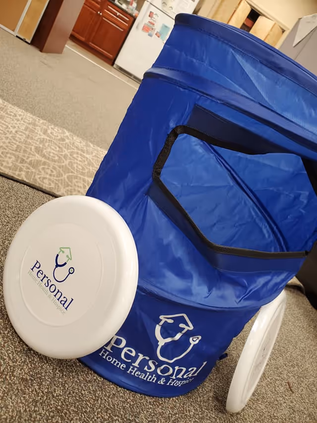 A blue Personal Home Health & Hospice care cart with a white lid in a hallway.