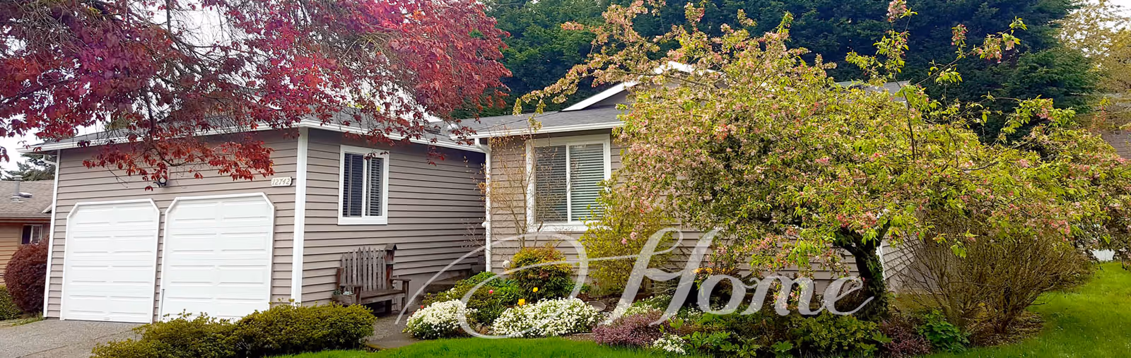 Single-story facility with gray siding, two white garage doors, and landscaped front yard.