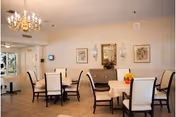 Dining room with multiple tables, upholstered chairs, chandelier, and wall art.