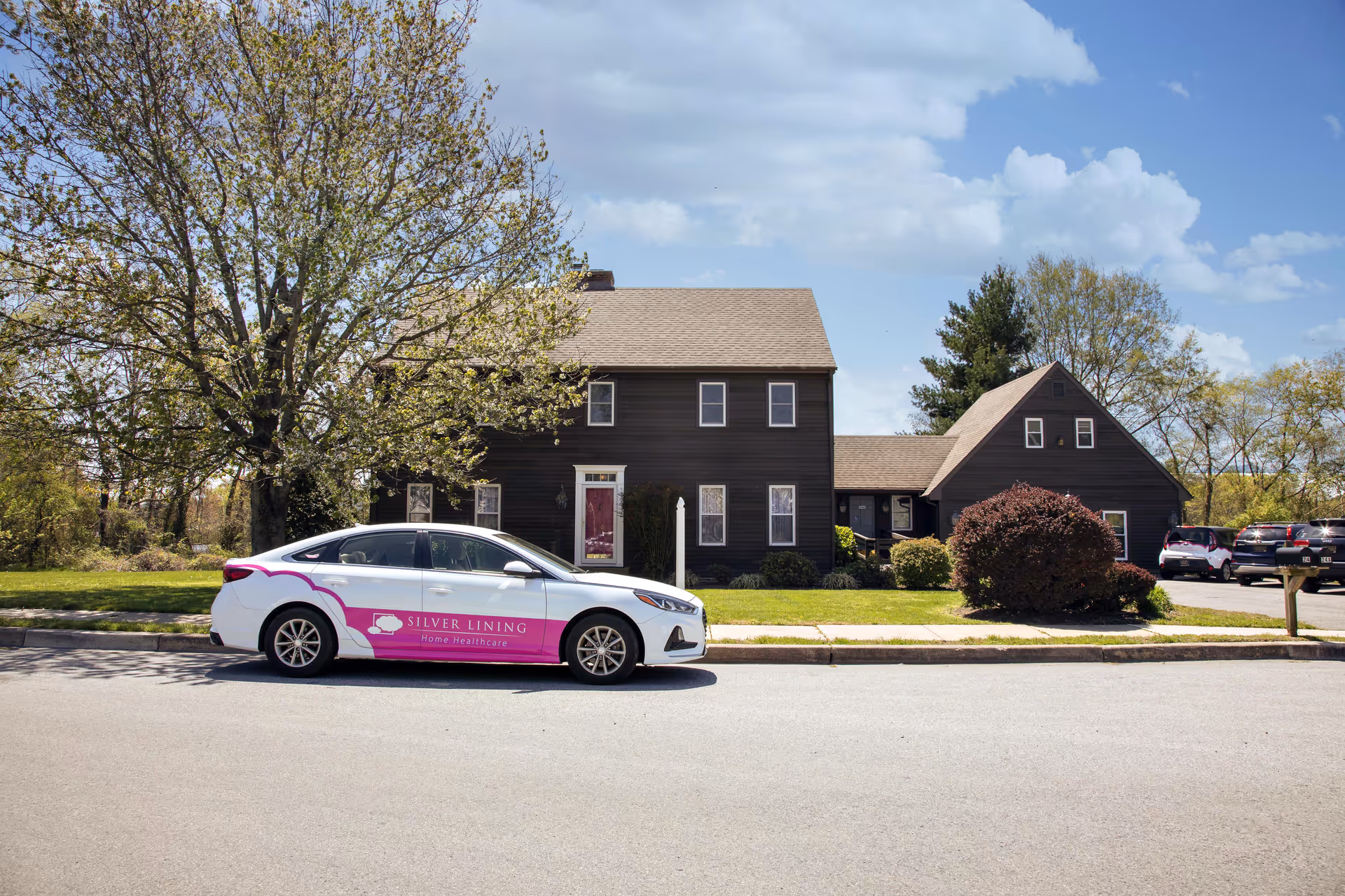 Dark wooden building with a Silver Lining Home Healthcare car parked along the street