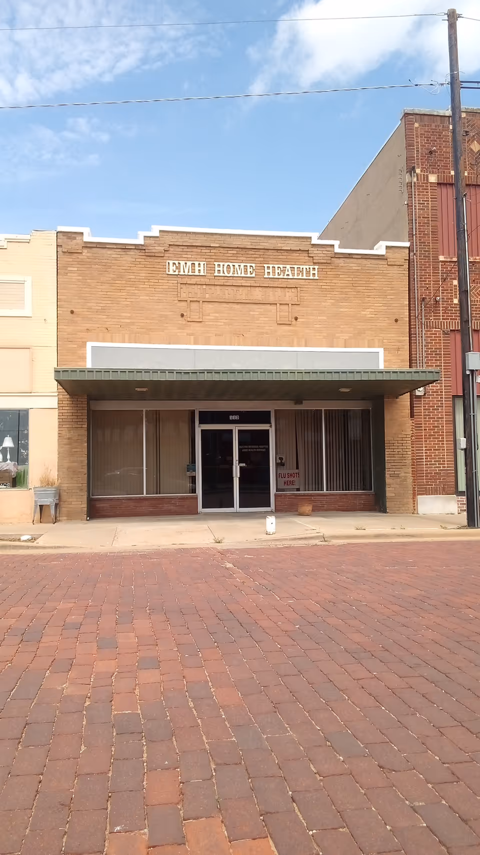 Brick storefront with Electra Home Health signage and glass entrance on a quiet street.