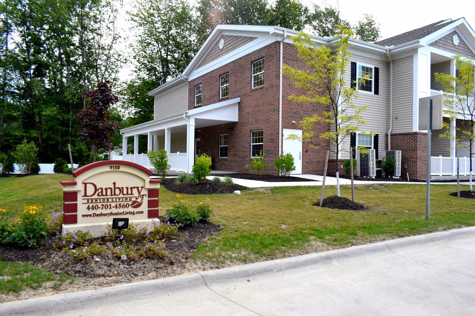 Exterior view of a Danbury Senior Living building with landscaped lawn and sign.