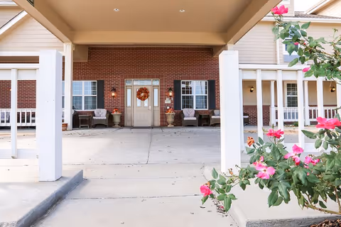 Front entrance of Vintage Park at Tonganoxie featuring brick facade, seating, and blooming flowers.