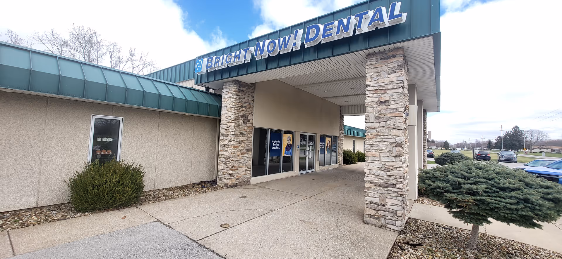 Exterior view of a building entrance with stone pillars and a Bright Now Dental sign