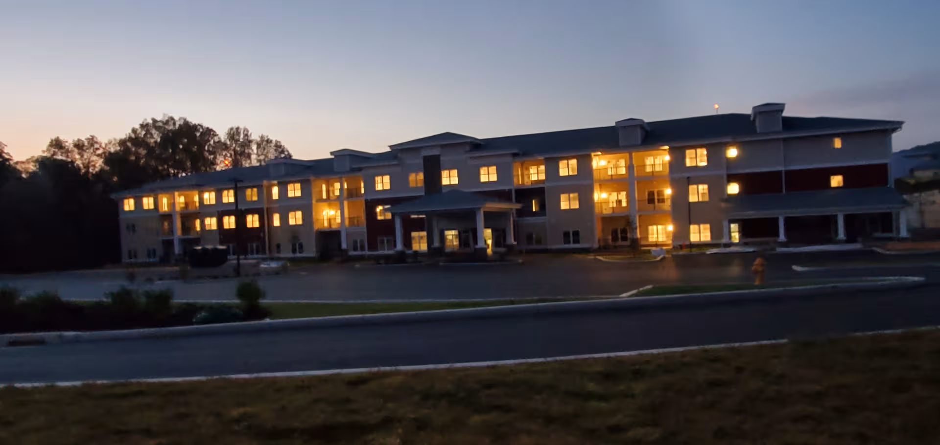 Exterior view of Keystone Place at Wooster Heights, building at dusk with lit windows.