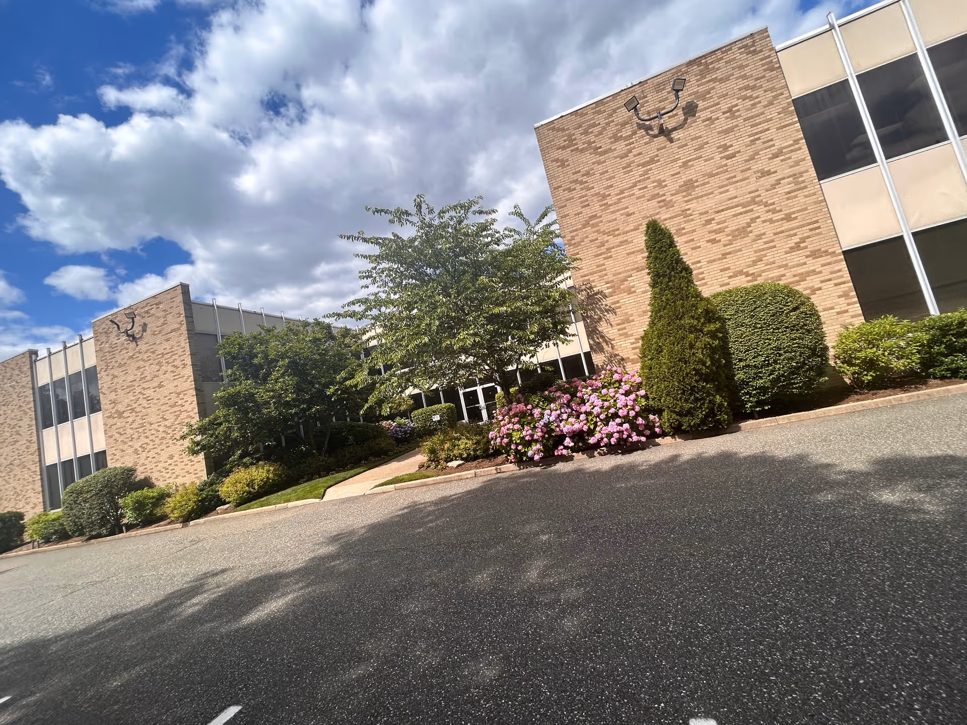 Exterior view of a brick senior care facility with landscaping and blue sky.