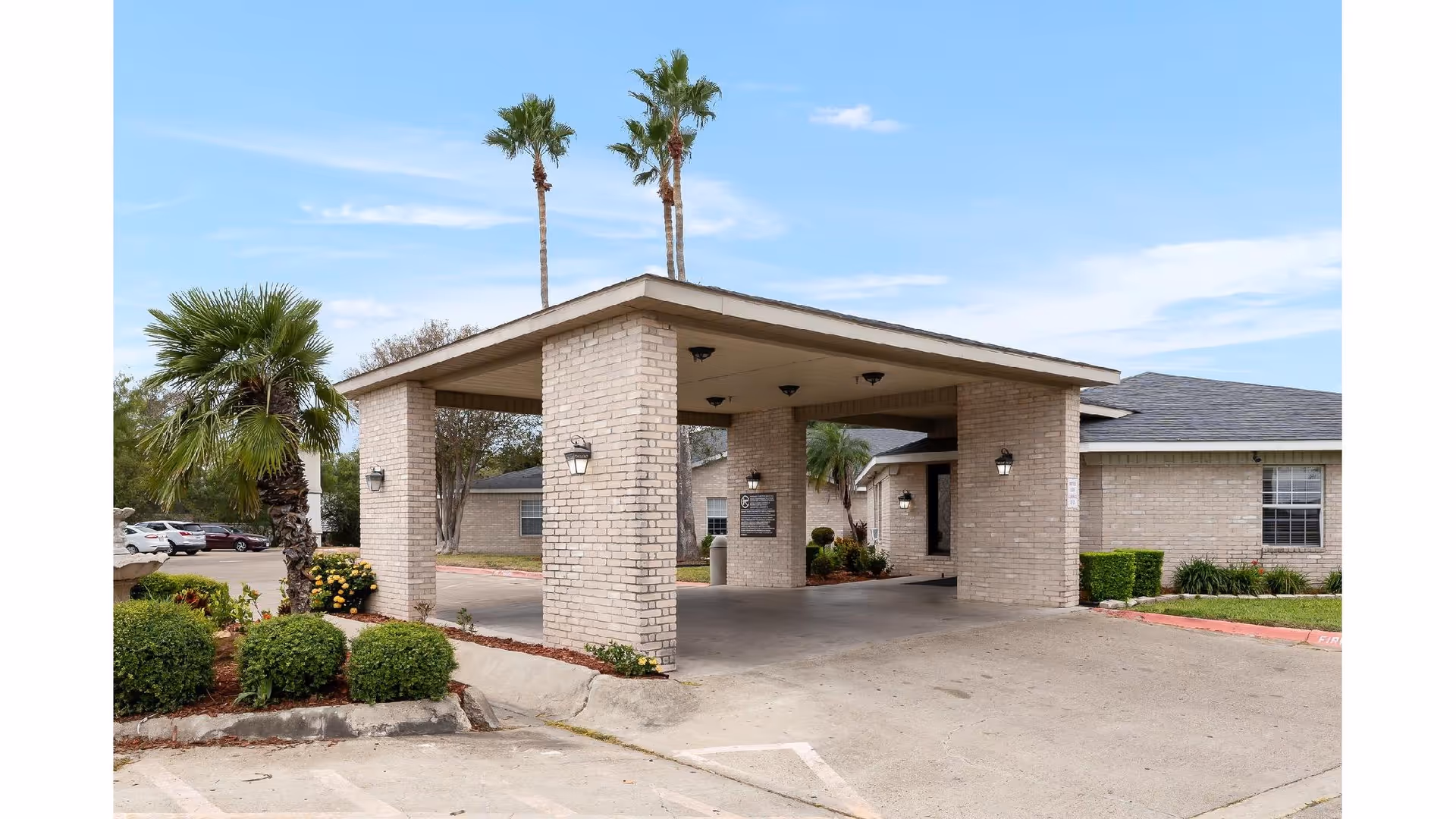 Brick entrance canopy with columns and landscaping leads to a senior care facility.