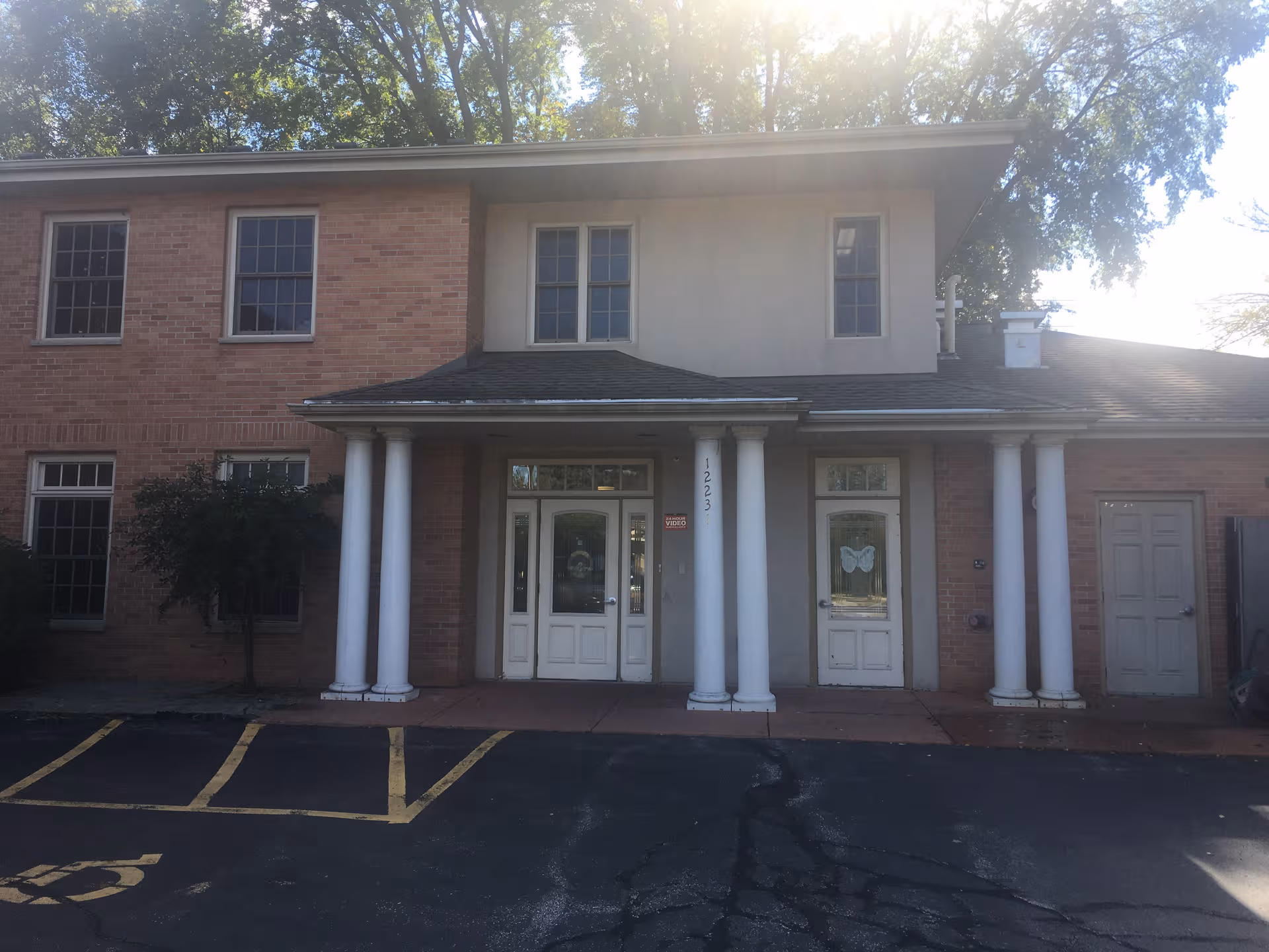 Brick senior living center with white columns and a double-door entrance in front.