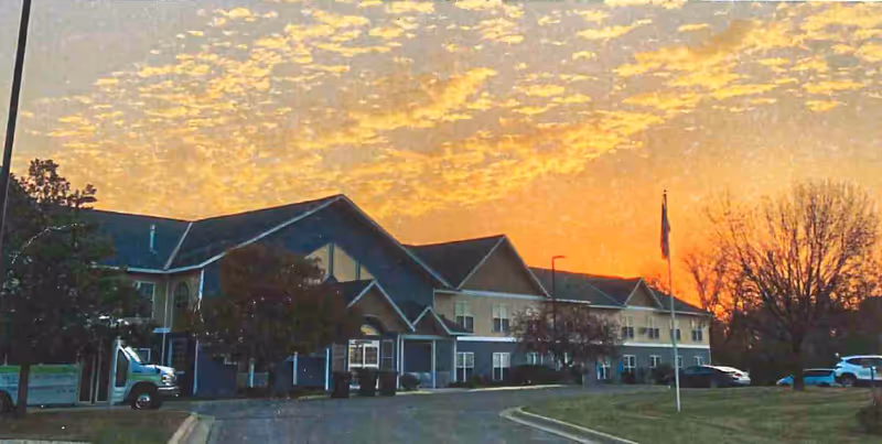 Sunset glow over Caldwell senior living facility with a large front entrance.