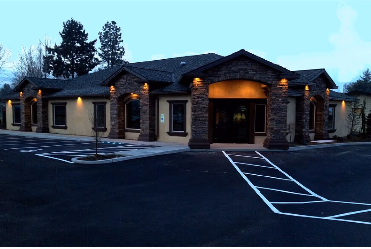 Front exterior of Chinook Home Health Care building with stone pillars and parking.