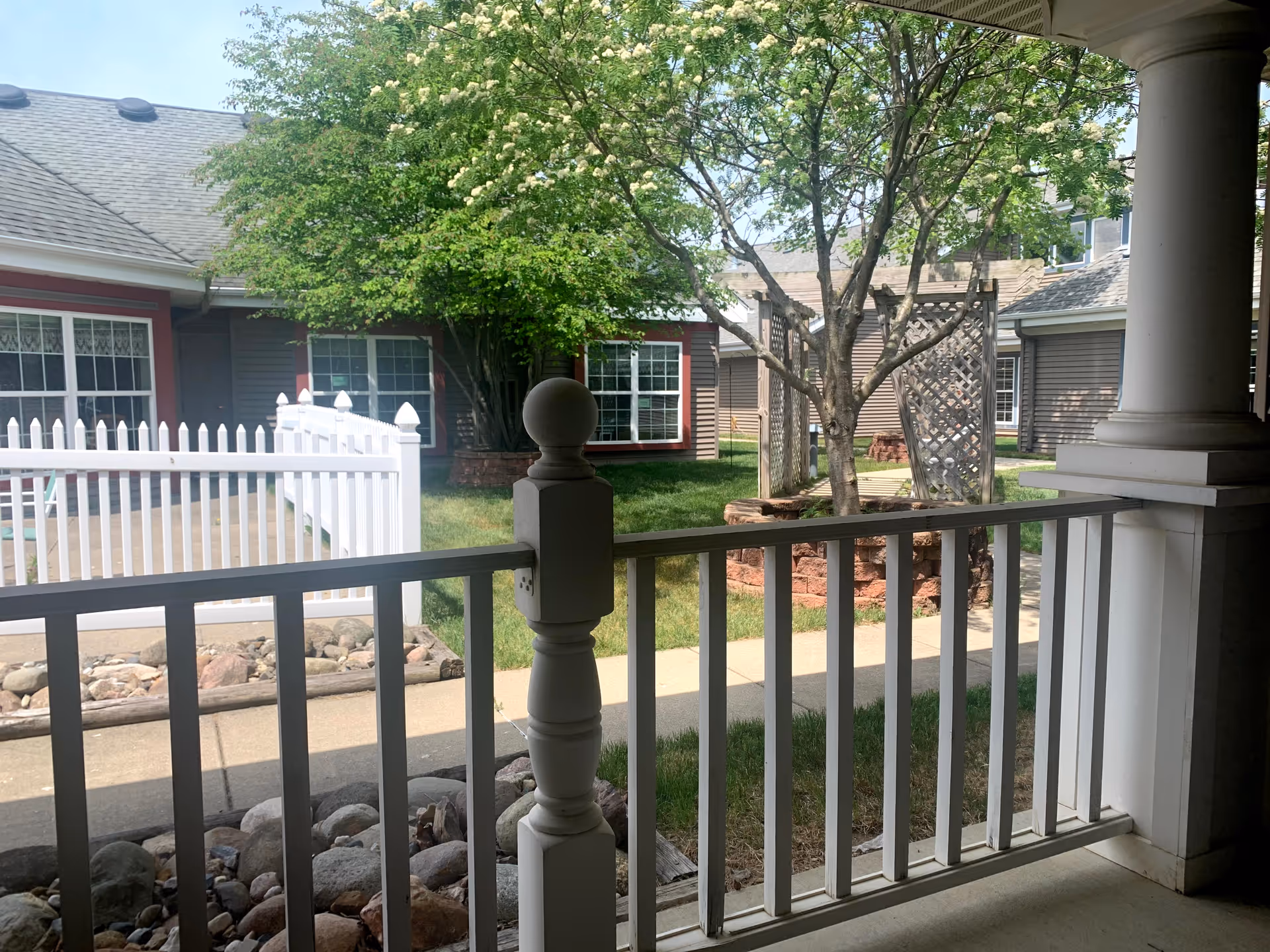 Front porch view with white railing, walkway, and greenery at Caretel Inns of St. Joseph.
