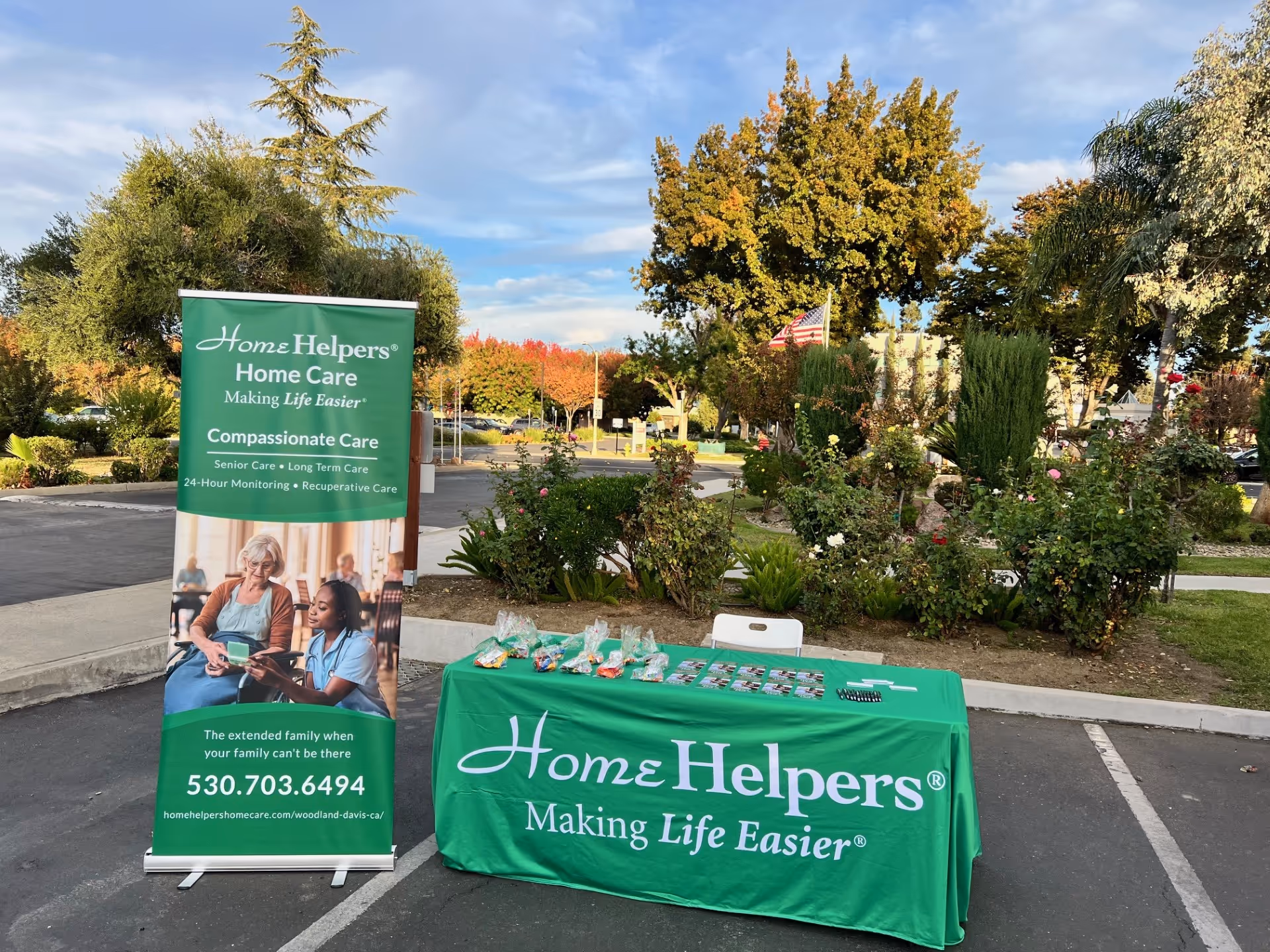 Outdoor display featuring a Home Helpers banner and table in a parking lot