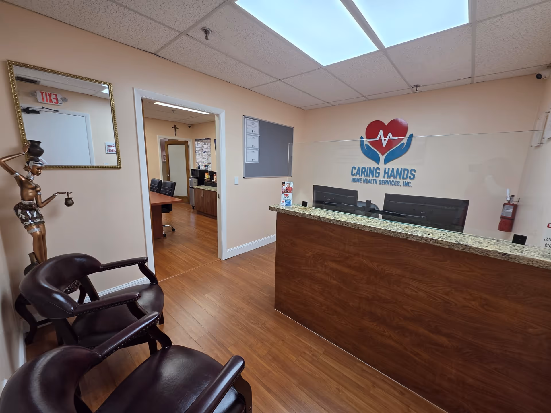 Reception desk with glass divider and Caring Hands logo in a waiting area.