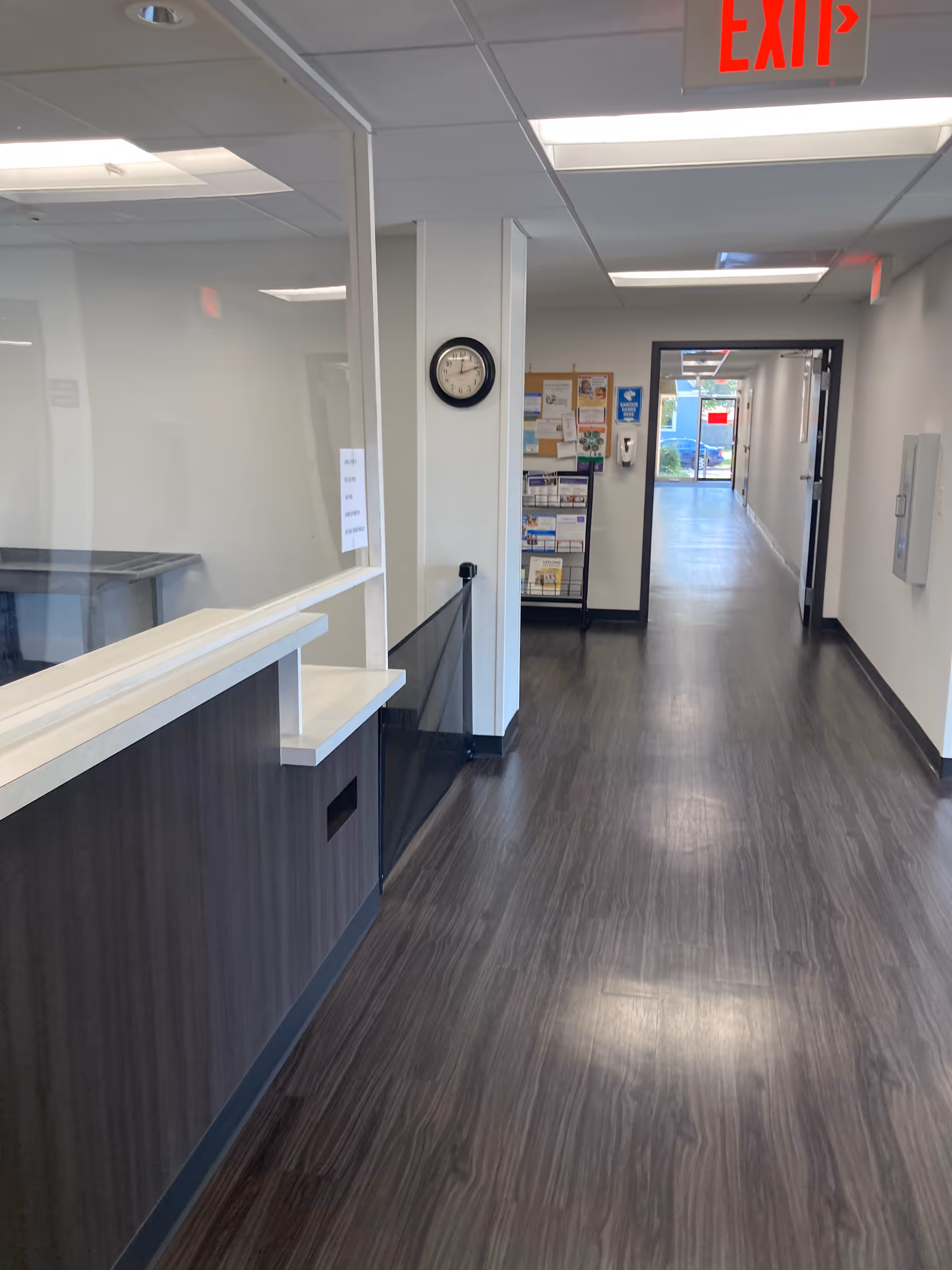 Indoor hallway of a senior living facility featuring a reception desk and exit sign.