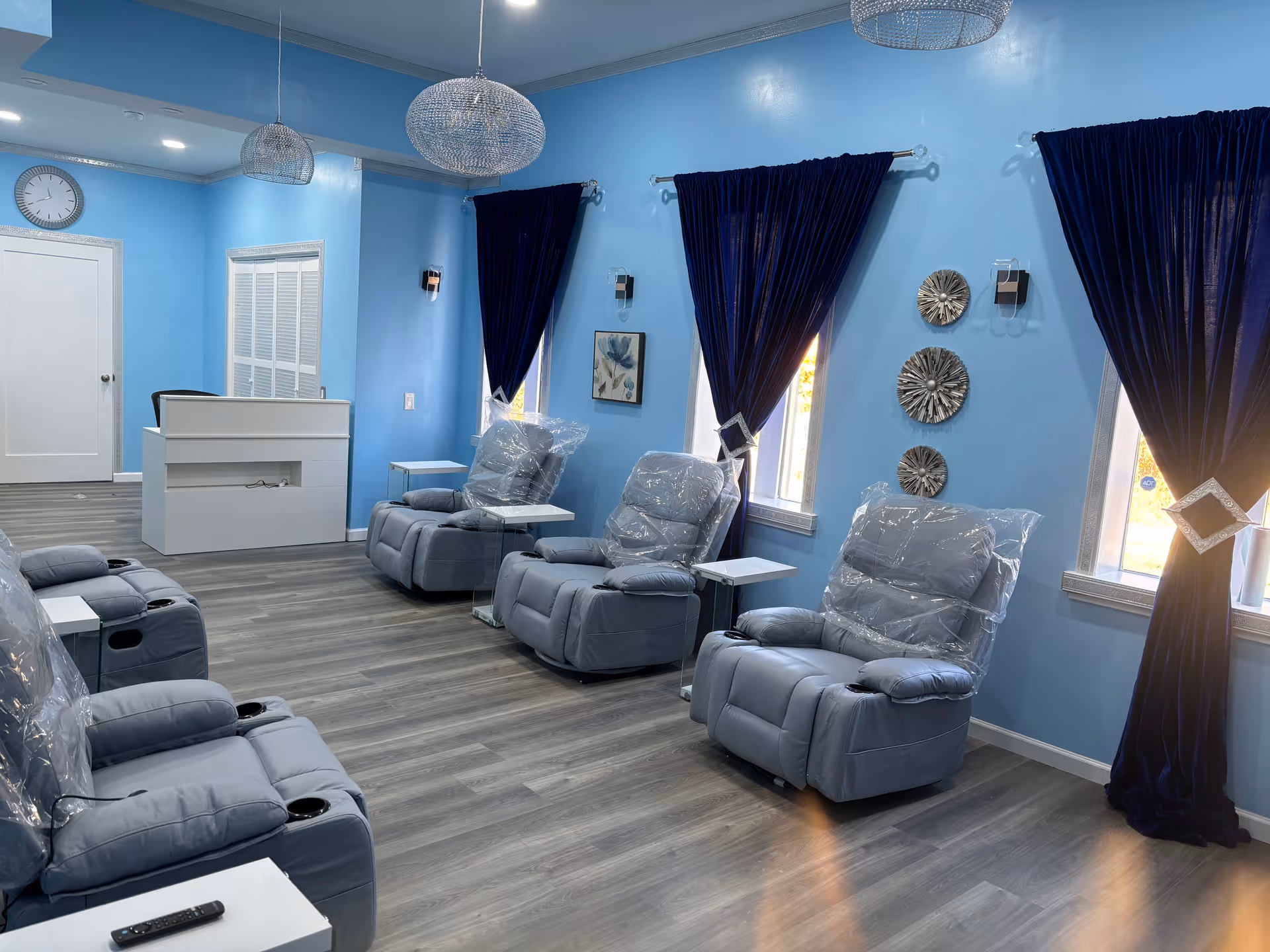 Blue-walled infusion lounge with reclining chairs, blue curtains, and a reception desk.
