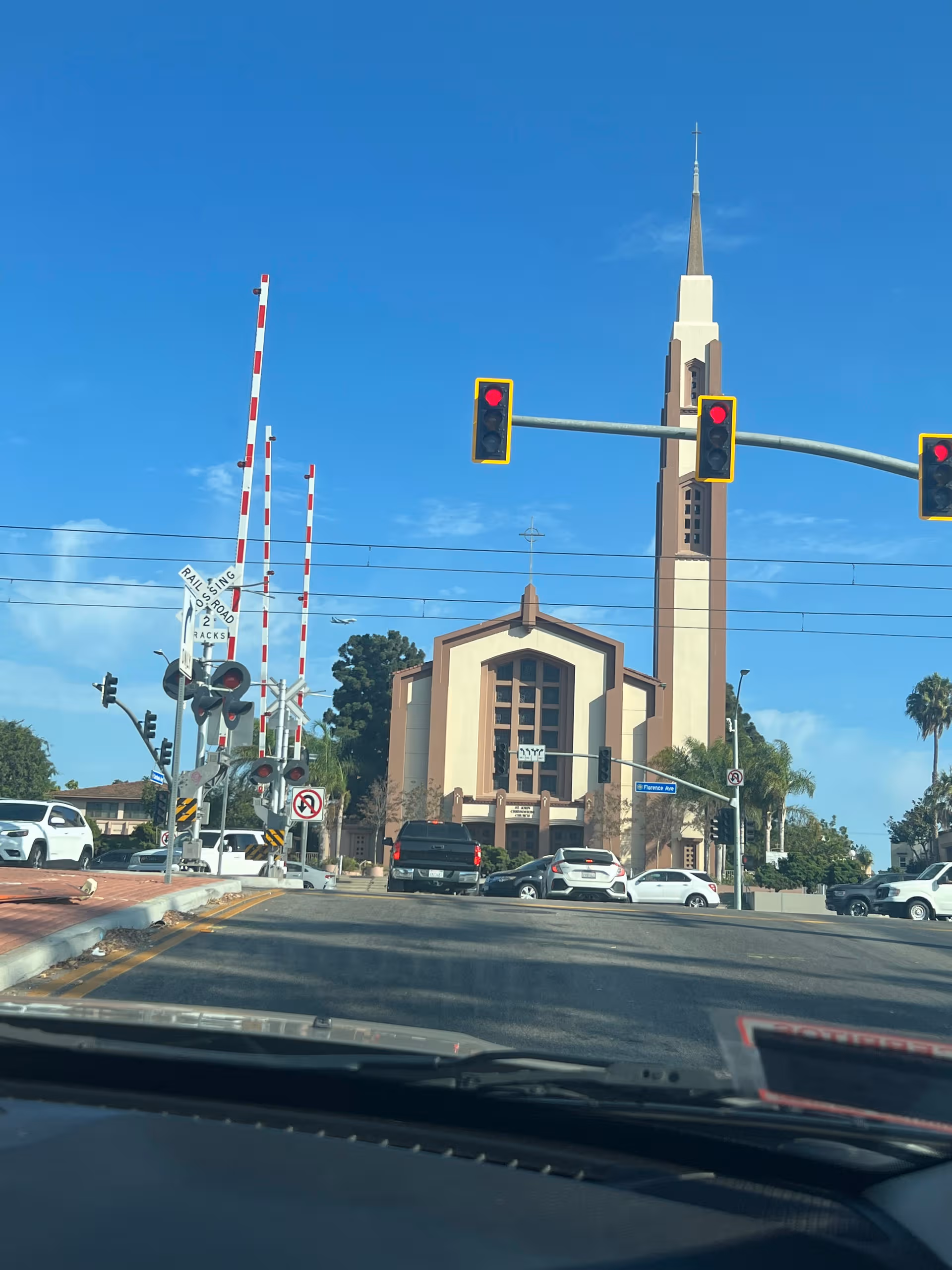 Exterior street view of a building with a tall spire beside a railroad crossing.