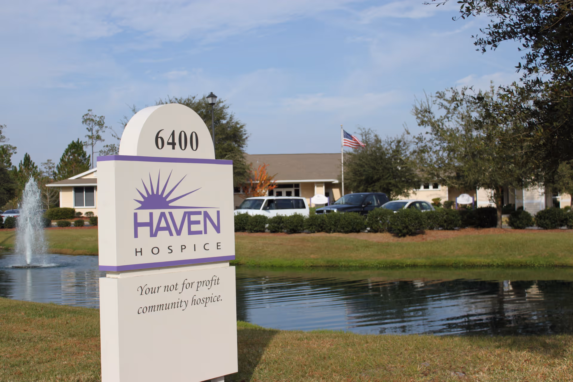 Exterior view of Haven Hospice sign beside a pond with a building.