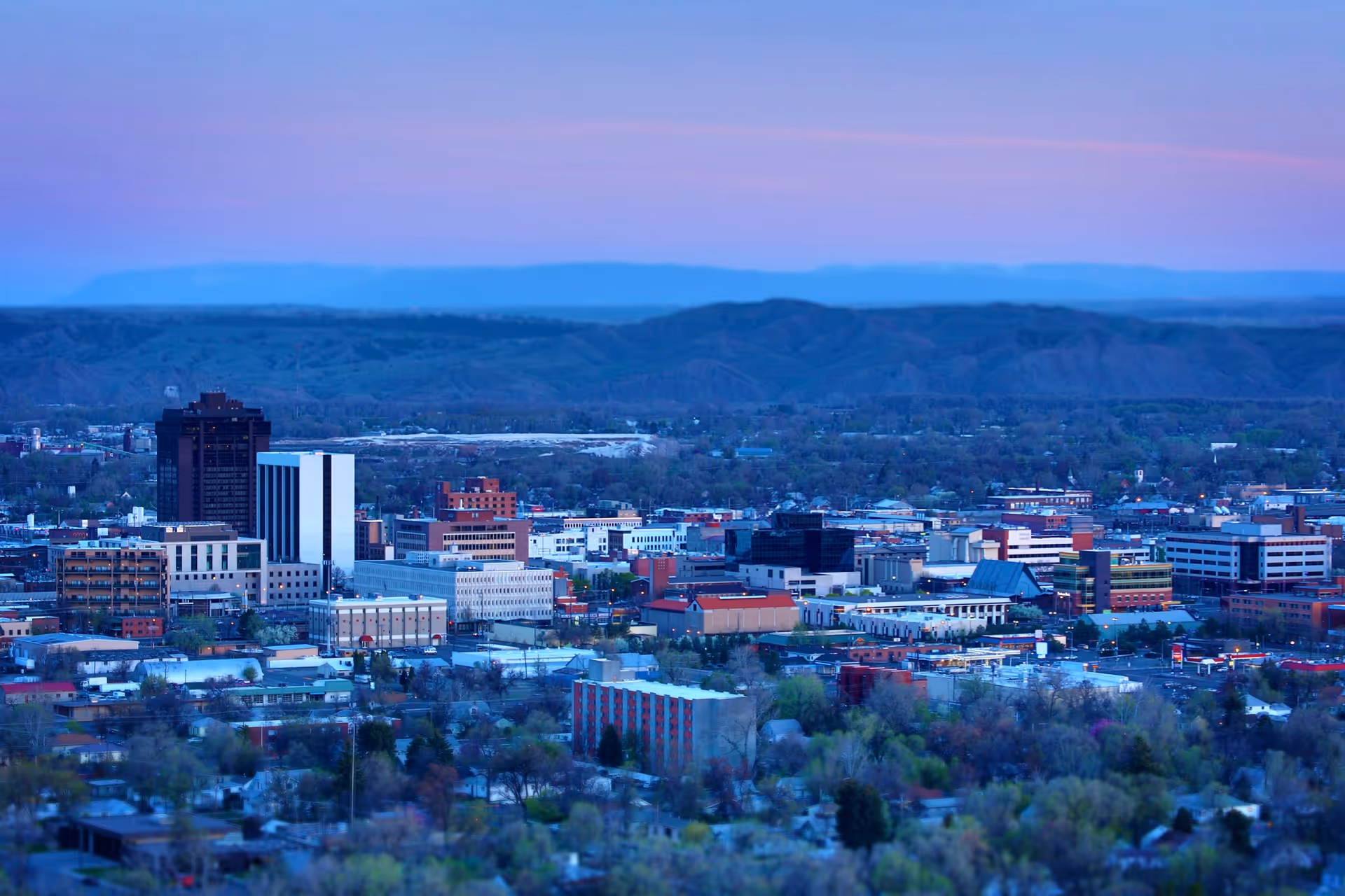 Montana town skyline with distant mountains at dusk.