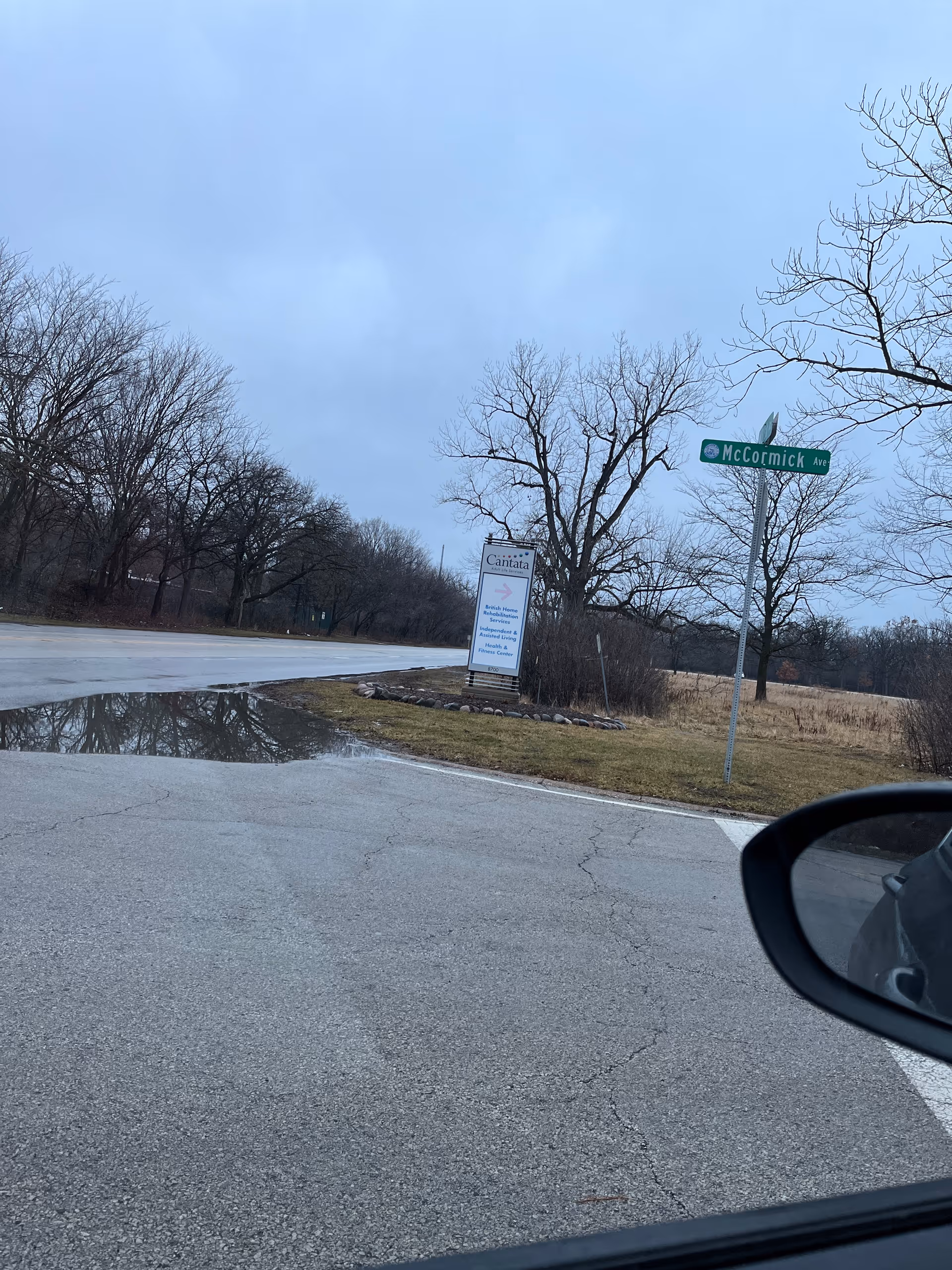 Roadside view featuring Cantata Adult Life Services sign, overcast sky, and leafless trees.