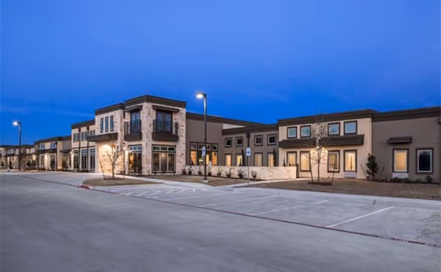 Front exterior view of Sky Vista senior living facility with a parking lot at dusk.